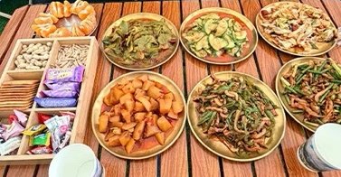 Stir-fried dishes and snacks served on a wooden table at Siguniang Base Camp.
