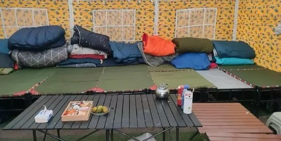 Inside a Base Camp tent: sleeping bags and mats laid out on a platform, with a low table in front.