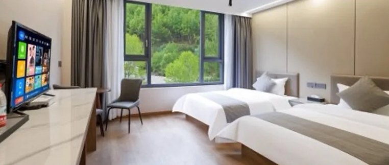 Standard twin room in the Siguniang town guesthouse, with large windows looking onto the forested hillside.