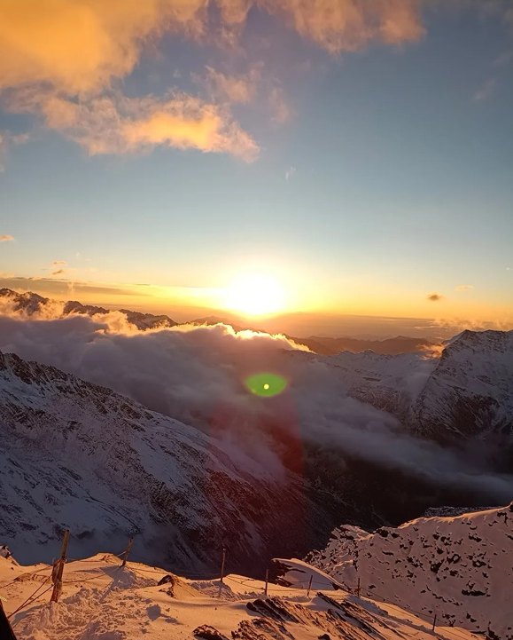 Sunrise above a sea of clouds seen from the ridge above Siguniang Base Camp, with first light on the snow.